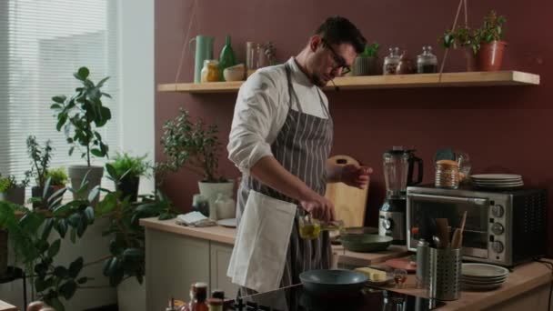 中镜头的年轻白种人男性厨师在做饭的时候倒油 并在热油锅上加黄油 — 图库视频影像