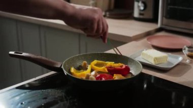 Tanımlanamayan bir aşçının biberleri közle çevirdiği kesme sahnesi.