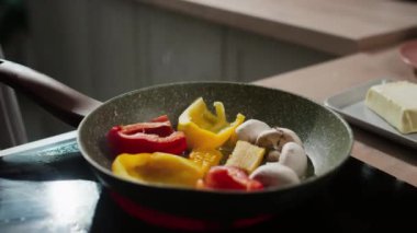 Tanınmayan bir erkek aşçının fırında tavada sebze pişirmesi.