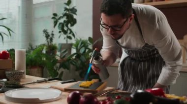 Gözlüklü ve aşçı üniformalı beyaz erkek şefin, mutfakta kızarmış mısır pişirirken kavurucu kullanırken orta boy fotoğrafı.