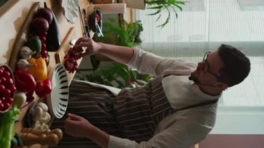 Taze sebze ve meyvelerle dolu ahşap masada yemek pişirirken beyaz erkek şefin orta boy portresi.