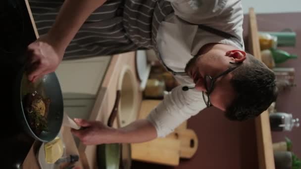 白种人男性厨师在厨房的平底锅里用融化的黄油烹调牛肉牛排的垂直中镜头 — 图库视频影像