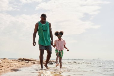 Babası, sahil boyunca yürürken kızıyla el ele tutuşmuş.