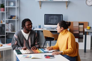 Ofiste masada otururken tasarımı tartışan iki meslektaş