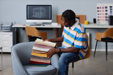 İç mimar, tekstil örneklerini inceliyor ve görevdeyken iç mimarlık için bir tane seçiyor.