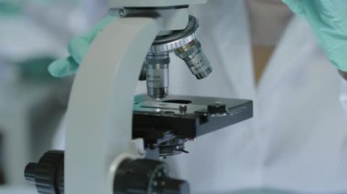 Modern laboratuardaki iş yerinde uzmanlık yaparken mikroskop kullanarak beyaz kadın mikrobiyolog 'u yukarı çekmek