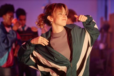 80 'lerin disko partisinde pembe ışıklarla dans eden, retro kıyafetli genç kızın belden yukarı portresi.