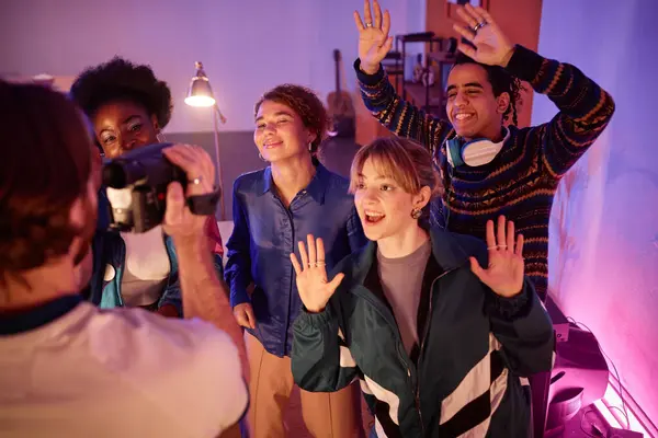 stock image Group of young friends having fun at house party with man holding retro video camera and filming home video