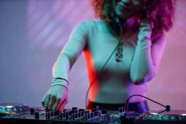 Genç bayanın DJ olarak yakın plan çekimleri neon ışıkta müzik yapıyor.