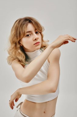 Beyazlı kadın dansçının dikey görüntüsü beyaz arka planda dans egzersizleri gösteriyor.