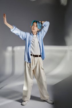 Gri arka planda duran Asyalı genç dansçının dikey görüntüsü