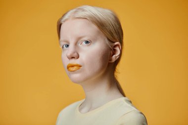 Albinizmli genç bir kadının en düşük moda portresi zıt sarı arka planda kameraya bakıyor.