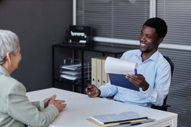 Gülümseyen siyahi adamın insan kaynakları çalışanı portresi iş görüşmesinde kıdemli adayla konuşuyor.