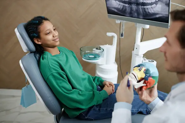 歯科クリニックの黒人の十代の少女の肖像画が椅子に座り 相談中に歯医者に耳を傾ける — ストック写真
