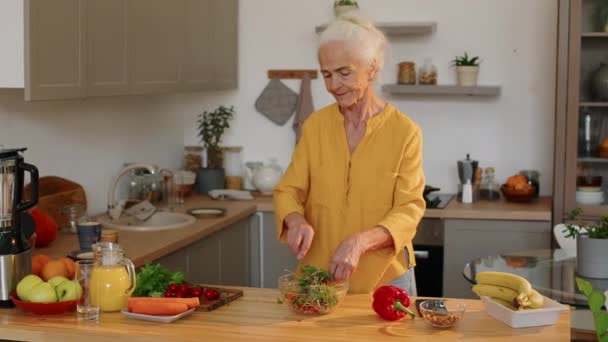 白种人老年妇女健康生活方式的中景照片 站在厨房餐桌旁 在碗里搅拌新鲜蔬菜沙拉当午餐 — 图库视频影像
