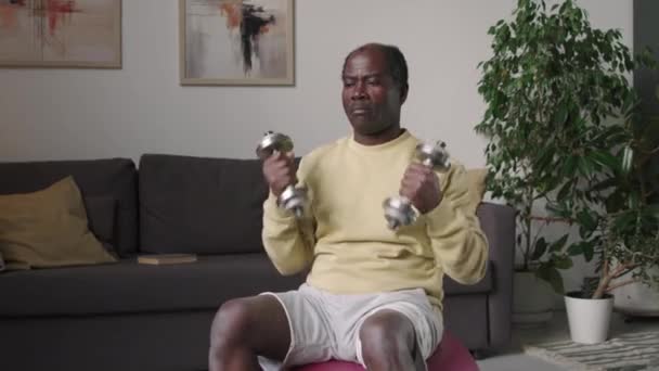 Μέτριο Πλάνο Του Ηλικιωμένου Μαύρου Άνδρα Ανύψωσης Αλτήρες Ενώ Κάθεται — Αρχείο Βίντεο