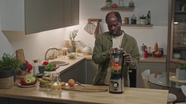 부엌에서 테이블에 믹서에서 비타민 스무디를 만드는 아프리카계 미국인 남자의 — 비디오