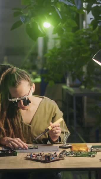 白种人年轻女电子工程师在生产厂工作时 身穿特殊眼镜 焊料母板及其部件并排坐的垂直中等照像机 — 图库视频影像