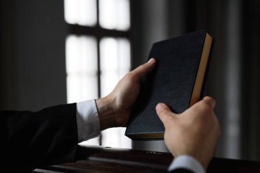 Kilisede dua ederken İncil 'i tutan rahibin yakın çekimi.