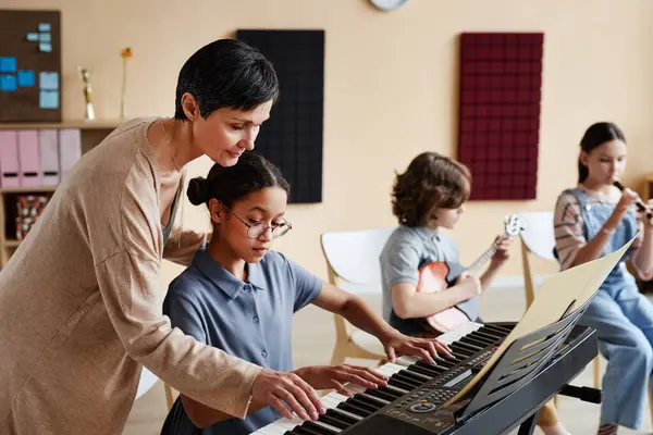音楽クラスで楽器を演奏するために子供を学ぶプロの教師 — ストック写真