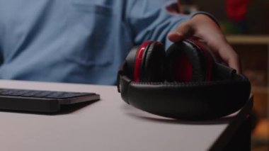 İki ırklı bir gencin mikrofonlu kulaklık takıp bilgisayar başında Neon Light Room 'da oyun sandalyesinde otururken ki görüntüsü.