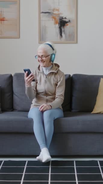 Κάθετη Πλήρης Μαχαιριά Χαρούμενη Καυκάσια Ηλικιωμένη Γυναίκα Ασύρματα Ακουστικά Κάθεται — Αρχείο Βίντεο