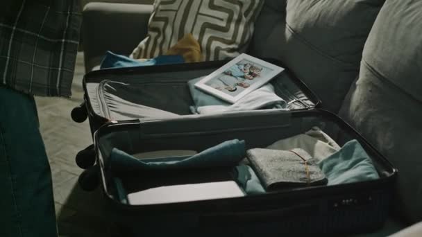 ローキーは 家庭内暴力と虐待のパッキングスーツケースを介して 暗い冷たいアパートを残している間 彼女の家族の写真をフレームで包装する女性のショットを切り取りました — ストック動画