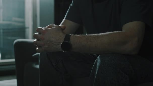 在黑暗的公寓里 一个无法辨认的成年人坐在沙发上 与妻子分居后从他的手指上摘下结婚戒指 — 图库视频影像