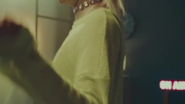 Baştan çıkarıcı genç beyaz kadın, yüksek bel mini şortlu, balıkçı ağı tayt giyiyor ve neon sarısı yarı kollu, yarı kollu üst kısmı açık havada dans hareketleri sergiliyor.