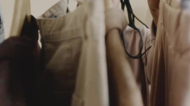 Siyahi kadın moda blogcusu yavaş yavaş raftaki moda kıyafetlerini seçiyor ve sosyal medya için yeni bir vlog oluştururken akıllı telefon kamerasında onları gösteriyor
