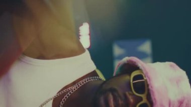 Genç Afro-Amerikan hipster 'ın dikey yavaş çekimi. Parlak y2k kıyafetli ve gözlüklü biri. Partide hip hop dansı yapıyor.