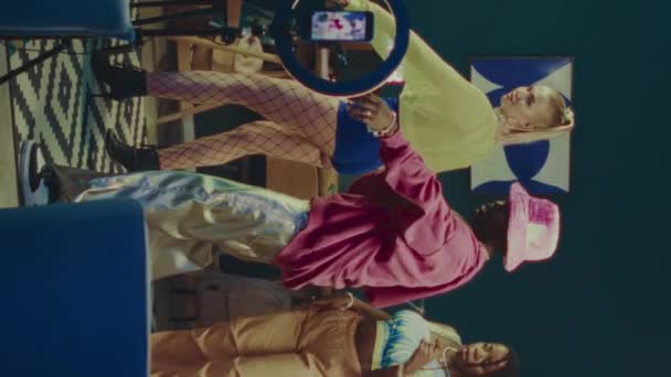 三脚のスマートフォンでソーシャルビデオのためのダンスビデオを撮影するY2K衣装を身に着けている3人の多民族の若いブロガーの垂直な全長の遅い動き — ストック動画