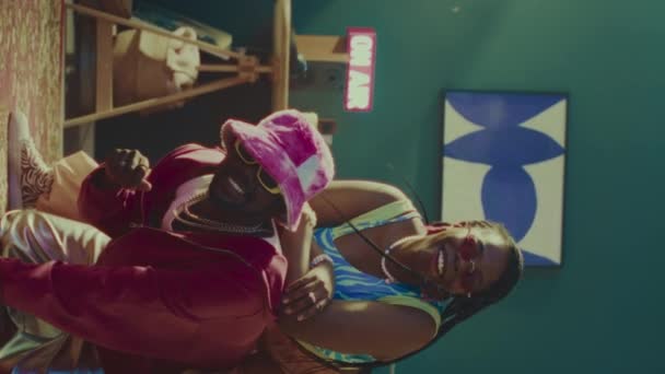 穿着五彩缤纷的Y2K服装的年轻的非洲裔美国舞女们的竖向肖像 在有花纹红地毯的阳光照射的老式公寓里摆姿势拍照 — 图库视频影像