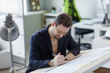 İş yerindeki sakallı mühendisin portresi çizimler ve planlar.