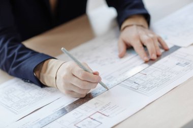 İş yerindeki yakın plan mühendisi, elinde cetvel tutarak plan ve planlar çiziyor.