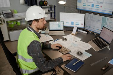 Ofiste başlık takan ve bilgisayar kullanan sakallı makine mühendisinin yan görünüm portresi