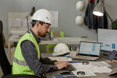 Ofisteki işyerinde başlık takan ve hesaplama ve tasarım için birden fazla bilgisayar aygıtı kullanan erkek mühendisin yan görünüm portresi, kopyalama alanı