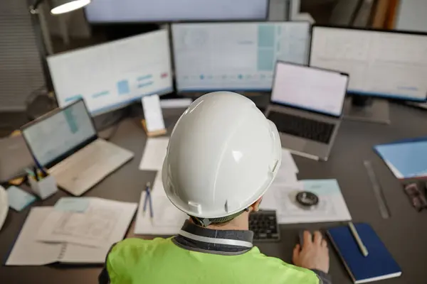 Top view of engineer wearing hardhat at workplace in office and using computer , copy space