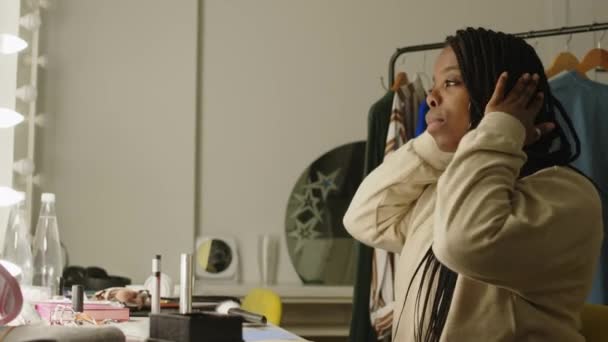 美籍非洲裔年轻女子在更衣室用灯泡在镜子前化妆和理发时的侧视中图 — 图库视频影像