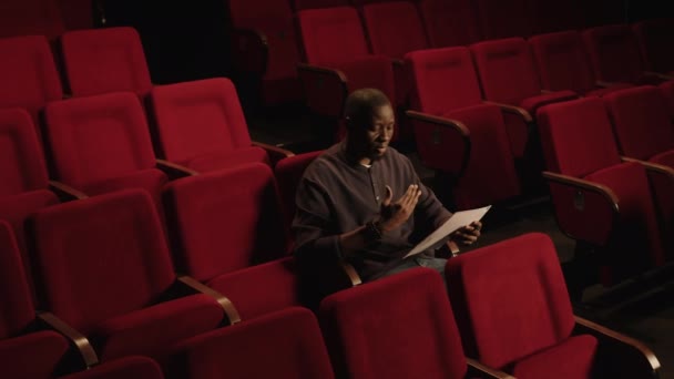 潘妮拍摄的年轻黑人男演员手拿着剧本坐在红色座位上排练试镜 — 图库视频影像