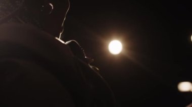 Sahnedeki stand-up konserinde sahne ışıklarıyla Afrika kökenli Amerikalı kadın stand-up komedyeninin konuşma yaparken arka plan görüntüsü.