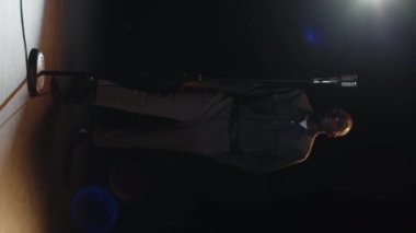 Genç siyahi erkek stand-up komedyeninin dikey, uzun ve yavaş çekimleri retro mikrofona yaklaşıyor ve karanlık sahnede komedi gösterisine başlıyor.