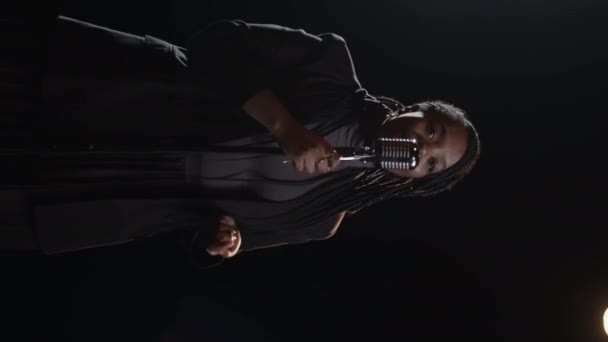 Вертикальный Снимок Молодой Чернокожей Женщины Стоящей Микрофоном Тёмном Фоне Исполняющей — стоковое видео