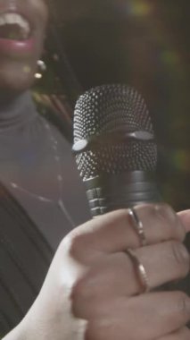 Sahnede spot ışıklarıyla mikrofonla konuşan genç siyahi kadın stand-up komedyeninin el kamerası görüntüsü yükseldi.