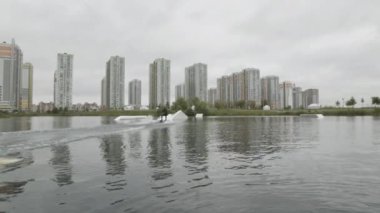 Gündüz vakti sörfçülerin gölde wakeboard numaraları yaptığı yavaş çekim.