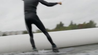 Mayo ve miğfer giyen aktif bir adamın gölde wakeboard çalışırken çekilen görüntüsü.