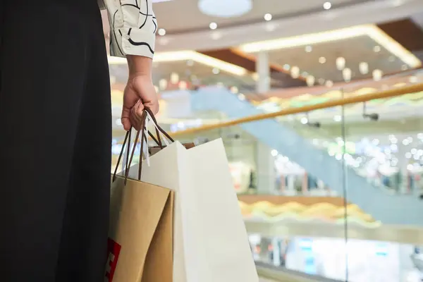 Close up of unrecognizable woman holding paper shopping bags in mall copy space