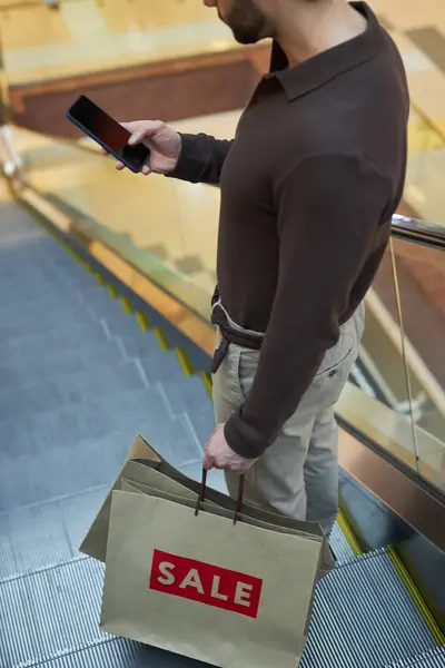 男子站在购物中心自动扶梯上使用智能手机的垂直截图 — 图库照片