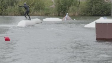 Profesyonel wakeboardcunun kablo parkında wakeboard çalışırken sürgüleyici kullanarak numara yaptığı arka plan görüntüsü
