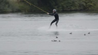 Profesyonel wakeboard sörfçüsünün kablo parkında süzülüşünü ve ekstrem su sporları çalışmasını izliyorum.